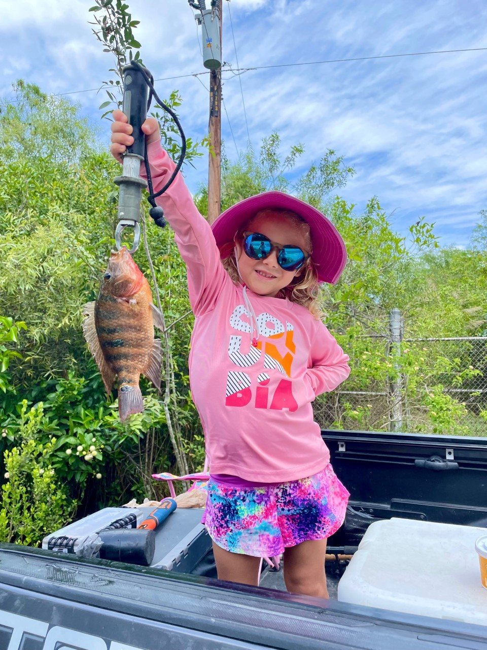 Mia Sipos proudly shows off her Mayan cichlid catch. These invasive fish put up a great fight and make great table fare.